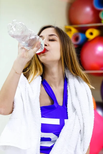 Młoda dziewczyna wody pitnej z butelki podczas treningu w gy — Zdjęcie stockowe