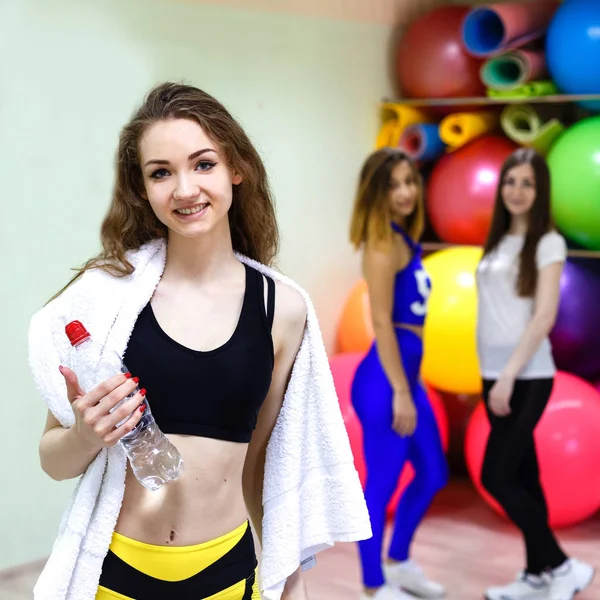 Mujer joven con una toalla sosteniendo una botella de agua mientras entrena —  Fotos de Stock
