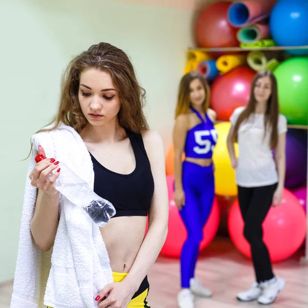 Jeune femme avec une serviette tenant une bouteille d'eau pendant l'entraînement — Photo