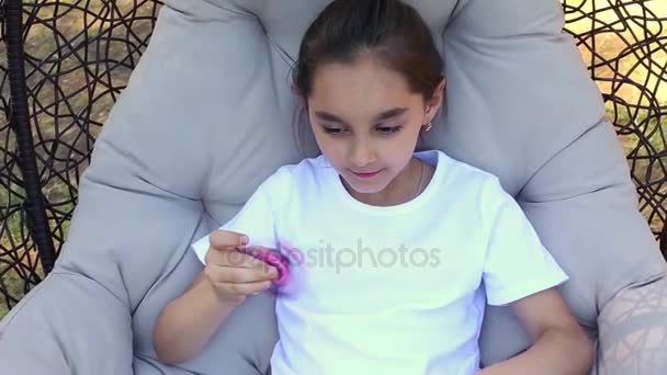 Unga kaukasiska tjej visar färdigheter genom att snärta spinnare med finger i parken sommaren. — Stockvideo