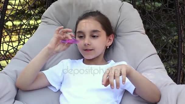 Young caucasian girl showing skills by flicking spinners with finger in the summer park. — Stock Video