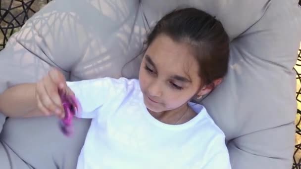 Fiatal kaukázusi lány mutatja a készségek a kiöltött spinners a ujját a nyári park. — Stock videók