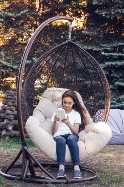 Beyaz tablet Pc, bir parkta otururken tutan mutlu beyaz kız