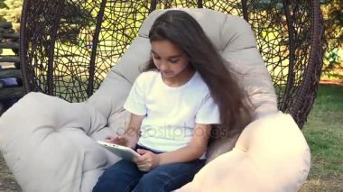 Beyaz tablet Pc, yaz gününde bir parkta otururken kullanan beyaz kız gülümseyerek..