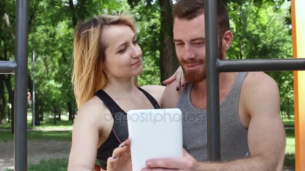 Счастливая молодая пара держит планшетный компьютер на открытом воздухе — стоковое видео