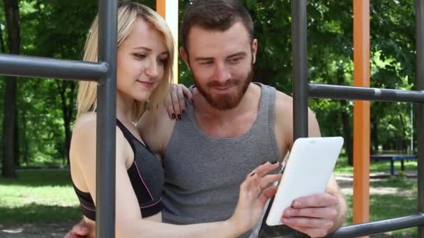 Szczęśliwa Młoda para trzymając tablet pc komputer na zewnątrz — Wideo stockowe