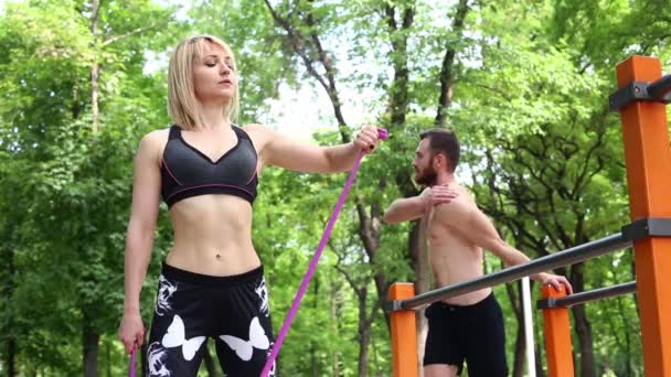 Sporty blonde girl and man is warming up before training in a park outdoor. — Stock Video