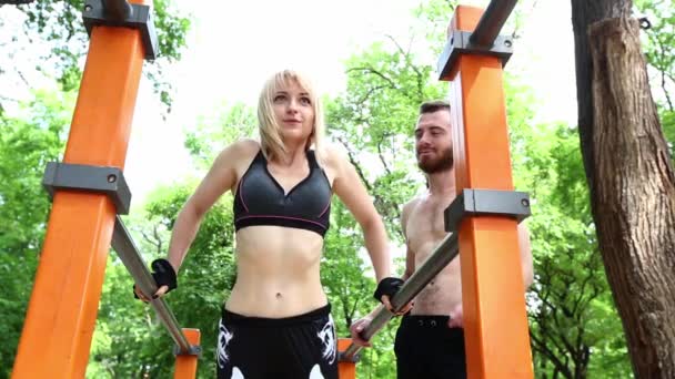 Sportos szőke lány és az ember melegszik, a parkban szabadtéri edzés előtt. — Stock videók