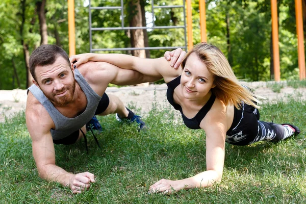 Genç sarışın kız ve sakallı adam parka egzersiz tahta yapıyor