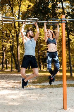 Genç sportif kız ve sakallı adam pull-up egzersizleri yapıyor 