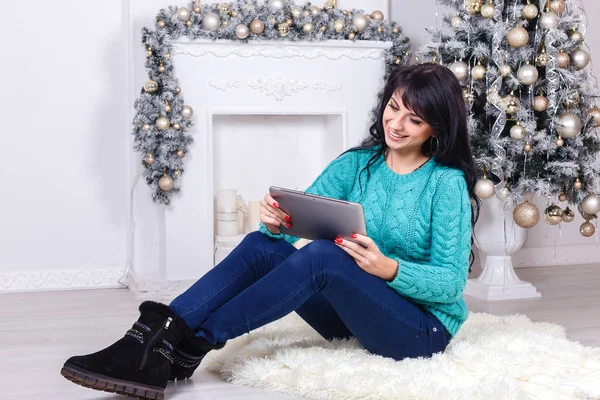Schönes Mädchen sitzt drinnen in Weihnachtsdekoration hält eine — Stockfoto