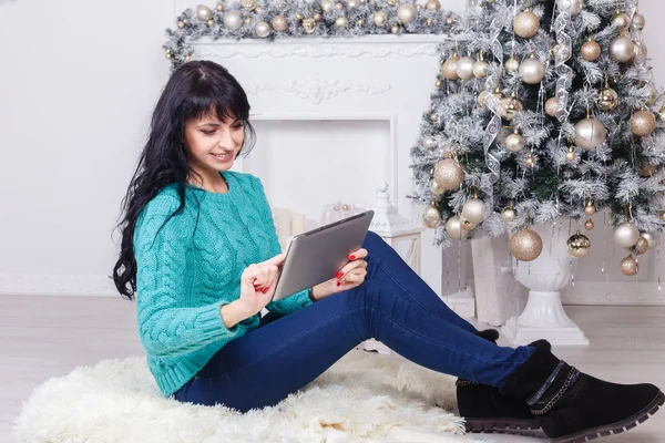 Glückliche kaukasische Frau sitzt drinnen in Weihnachtsdekoration uns — Stockfoto