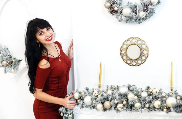 Gülümseyen bir christm kırmızı elbise sitanding genç esmer kadın
