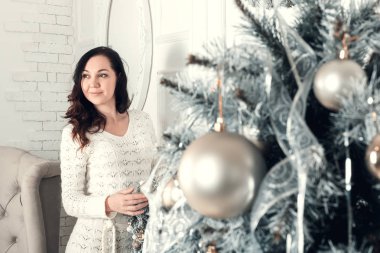 Noel'de köknar ağacının yanında duran genç ve güzel esmer kadın 