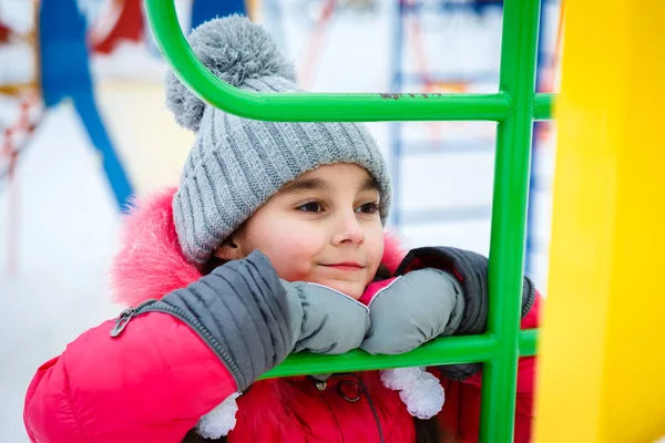 Fröhliches Mädchen spielt bei winterlichen Frosttagen auf einem Spielplatz. — Stockfoto