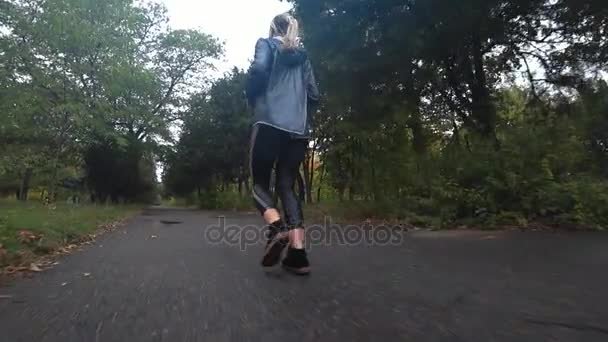 Beautiful young blonde girl is running in park at rainy day, doing sports, a healthy lifestyle.. Slow motion. — Stock Video