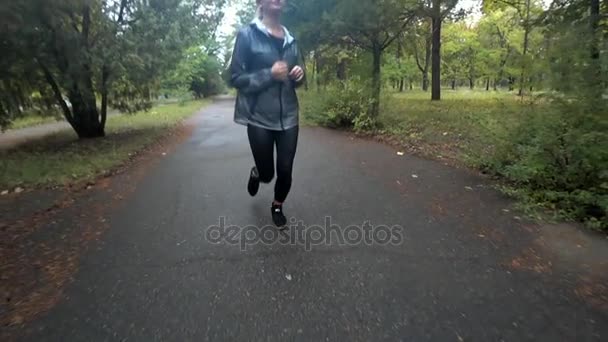Szép fiatal szőke lány fut park esős napon, a sportot, az egészséges életmód. Lassú mozgás. — Stock videók