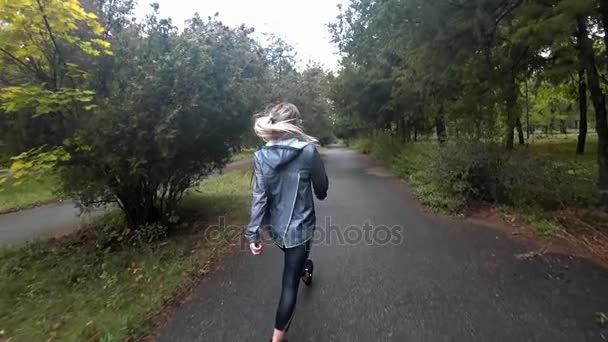 Hermosa joven rubia con el pelo largo caminando en el parque en un día de otoño lluvioso.. Movimiento lento . — Vídeos de Stock