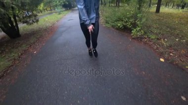 Yağmurlu bir sonbahar gününde parkta yürüyüş uzun saçlı güzel genç sarışın kız... Ağır çekim.