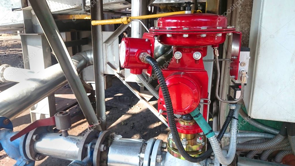 Big red valve close up on hydraulic system in industrial plant.