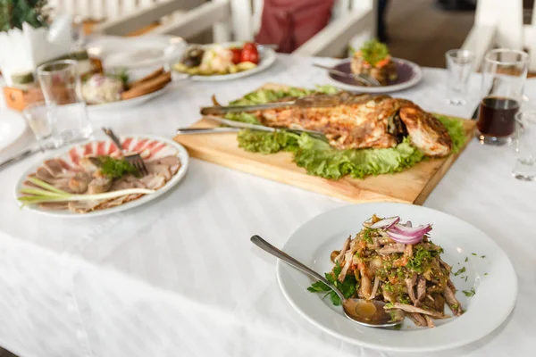 Pesce fritto e piatti su un tavolo da banchetto in un ristorante — Foto Stock