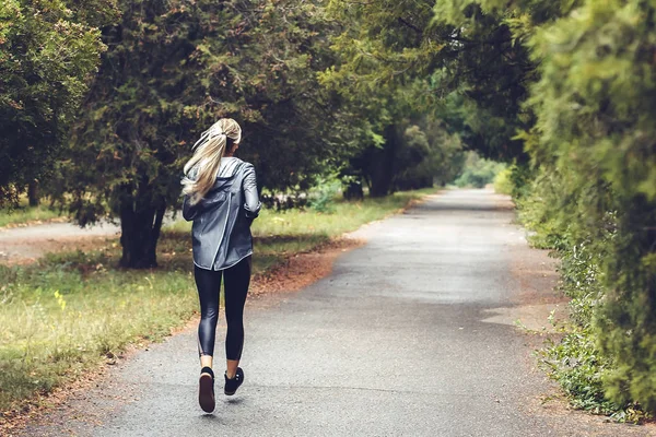 Красивая молодая блондинка с длинными волосами бегает в парке — стоковое фото