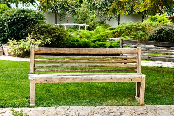 Bangku kayu kosong di taman kota. Tempat yang bagus untuk bersantai di musim panas. — Stok Foto