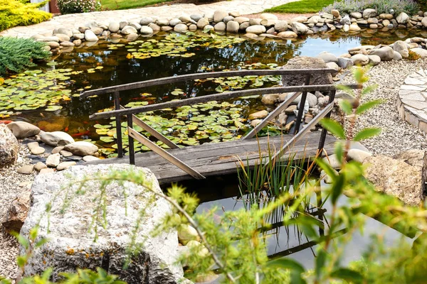 Puente de madera retro sobre el estanque con nenúfares en una ciudad pa — Foto de Stock