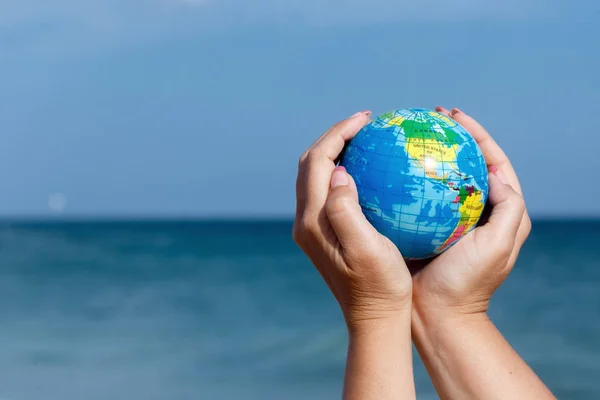 Mujer sosteniendo globo de la Tierra en un fondo del mar . —  Fotos de Stock