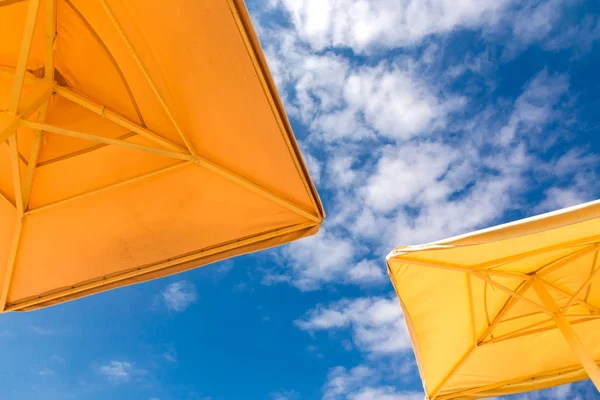 Plaj şemsiyeleri mavi bulutlu gökyüzü arka plan, alttan görünüm. — Stok fotoğraf