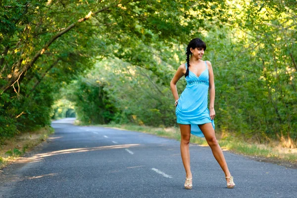 Sexy young brunette girl walking on the empty road at summer day — Stock Photo, Image