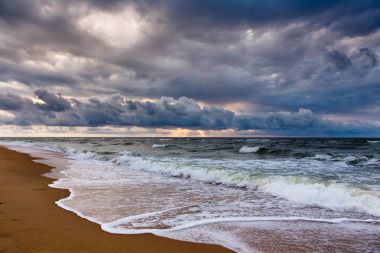 Bir sabah deniz manzarası üzerinde dramatik gökyüzü. Sunrise kumlu bir plaj üzerinde.