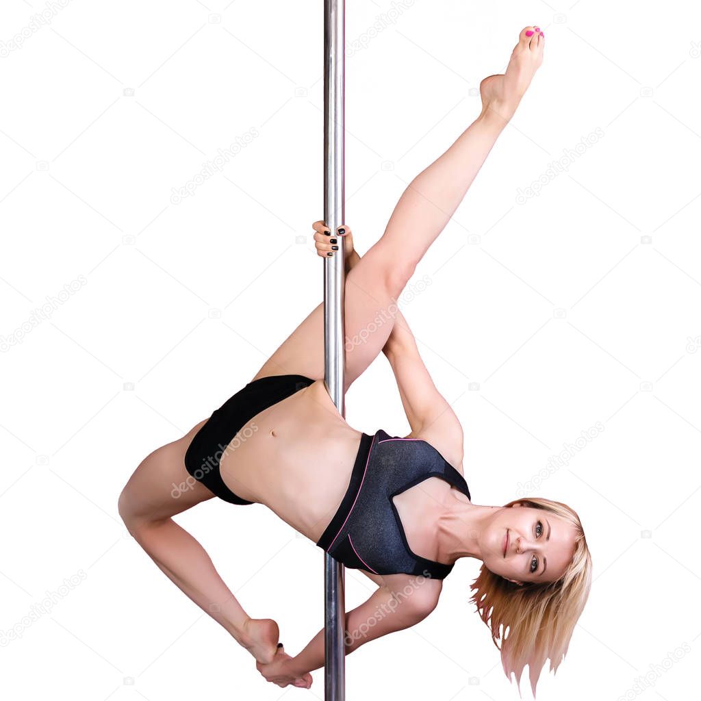 Young athletic blond girl  doing strength exercises on a pylon.