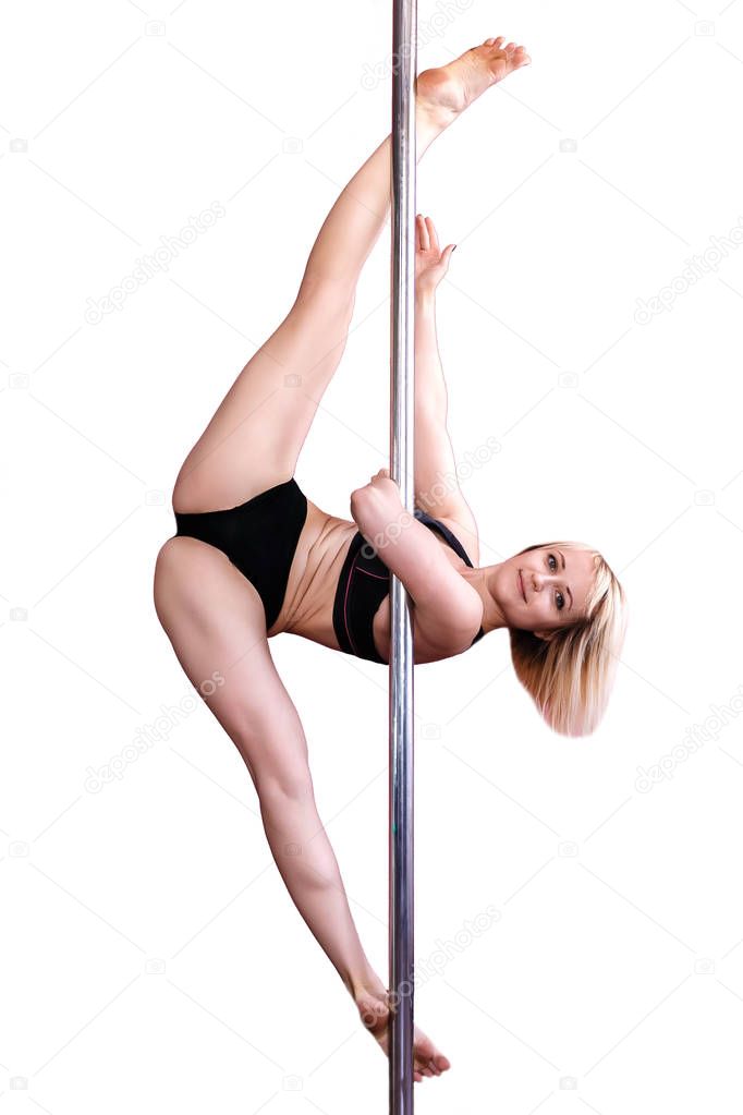 Young athletic blonde girl doing strength exercises on a pylon.