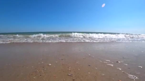 Las olas del océano cubren una cámara en una hermosa playa de arena en un día soleado de verano. Disparos para cámara de acción desde un ángulo bajo . — Vídeo de stock