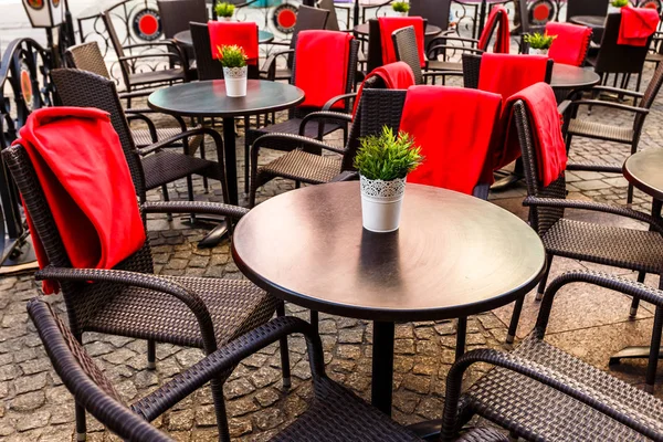 Empty tables and wicker chairs on paving stones in a cafe in old — Stock Photo, Image