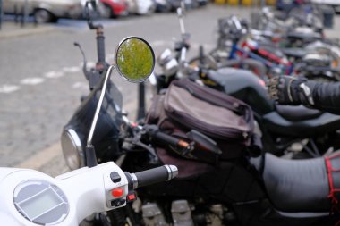 Beyaz mobilet ve güçlü siyah motosiklet grubu şehrin turistik merkezindeki kaldırımda bir sıra halinde park halindeler..