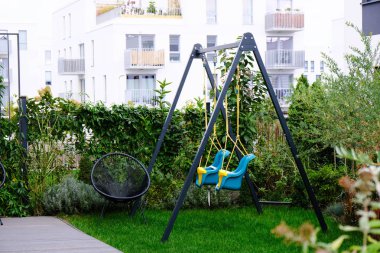 Modern yerleşim bölgesinin rahat avlusunda bir çocuk parkında duble salıncak.
