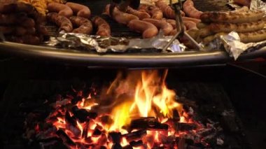 Domuz eti, çiğ et ve ızgara sosis açık ateşte büyük bir tavada kızartılır. Açık hava kafesi panayırdaki turistler için bir ziyafet hazırlıyor..