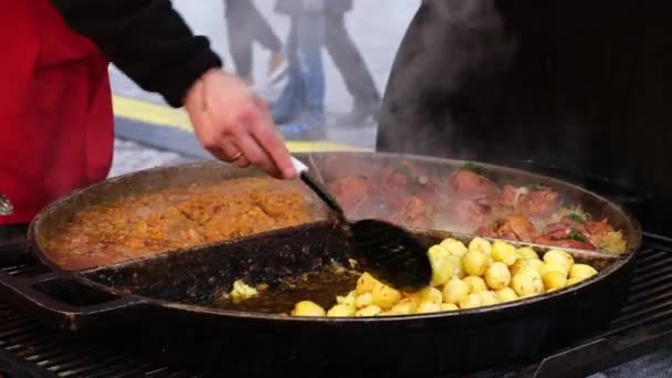 销售商们在室外咖啡馆的一个大圆盘上煎新鲜的肉和土豆 在展会上招待饥饿的游客 — 图库视频影像