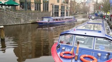 Amsterdam, Hollanda - Ocak 2020. Turistlerle dolu mavi zevk teknesi tarihi şehir merkezinde kanal boyunca seyahat ediyor..
