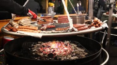 Domuz eti, çiğ et ve ızgara sosis açık ateşte büyük bir tavada kızartılır. Sokak kafesi panayırdaki turistler için bir ziyafet hazırlıyor..