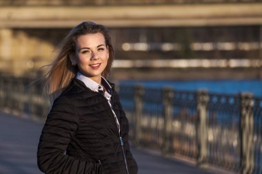 Güneşli bir günde şehrin tepesinde duran gülümseyen güzel kızın portresi..