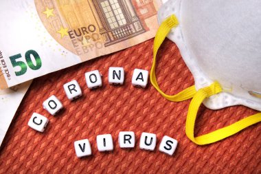 Metin Coronavirus kelimesi, beyaz koruyucu maske, Avrupai banknotlar Avro kumaş dokulu arka plan.
