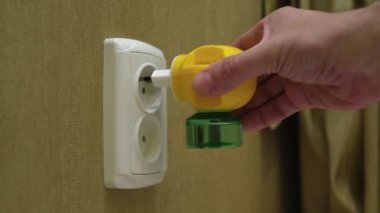 Erkek El Fişi Elektrik Sıvısı Sivrisinek Kovucu Bir odanın duvarındaki elektrik prizine.