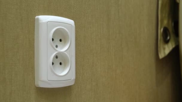 Manliga handpluggar strömkabeln till eluttag på en vägg i ett rum. — Stockvideo