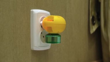 Yatak odasındaki bir duvardaki elektrikli sivrisinek kovucunun elektrik prizine yakın çekimi. Kamera hareket ediyor. Çekim yap..