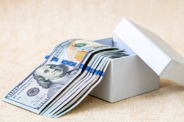 Beyaz hediye kutusunda 100 dolarlık banknotlar var..
