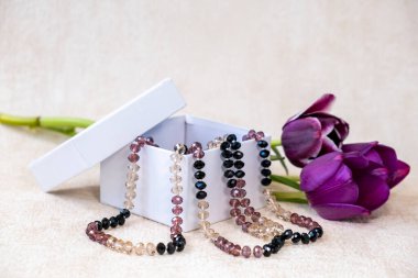 Burgundy renkli laleler, beyaz bir hediye kutusunda kadın boncukları. Merak ediyorum