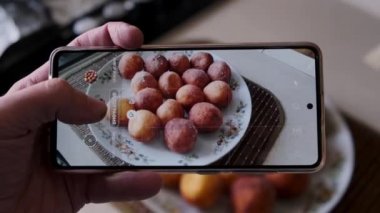 Erkek yemek blogcusu telefonla tabakta lezzetli ev yapımı çörek peynir toplarının fotoğrafını çekiyor. Eller yukarı..